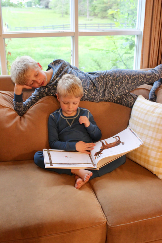 Brothers reading together while wearing pact pajamas