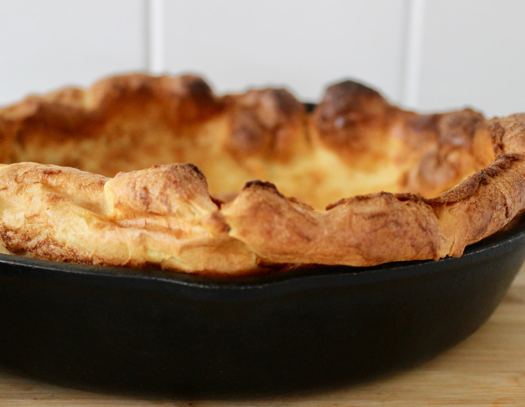 Beautiful Dutch baby edges popping up from an iron skillet