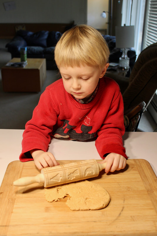 Child rolling out peanut butter play dough