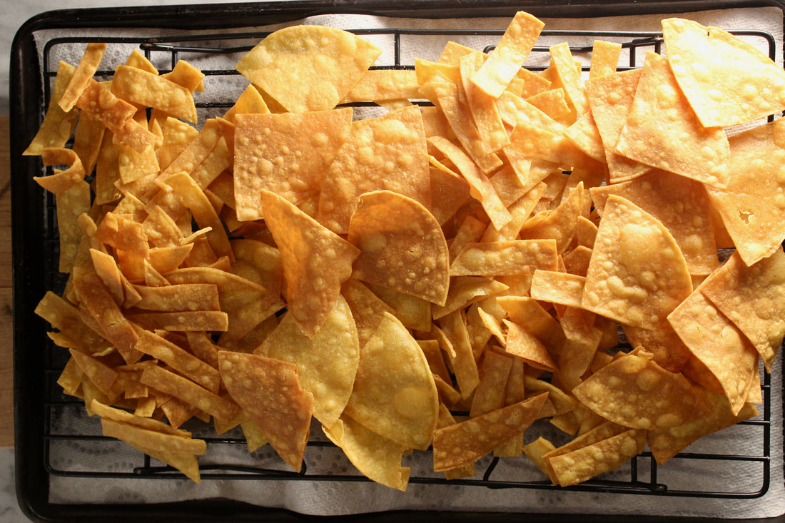 Tortilla chips on a cooling rack over paper towel lined pan